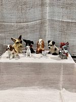 Front view of all eight dog figurines arranged in a row on a fabric-covered platform