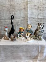 Photo of eight vintage ceramic figurines including tall swan, owl, fox pen holder, and children figurines