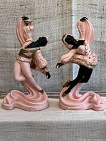 Front and side views of the pair of 1960s ballet dancer chalkware statues with pink and black paint.