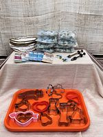 Full lot view showing orange trays, metal cookie cutters, floral decoration bags, sugar pincers, seam binding packs, and saucer protector bag.