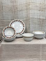 Full set of vintage dishes including side plates, fruit nappies, and berry bowl showcasing brown, orange, and yellow rim designs.