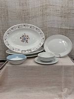 Overview of entire dishware set showing floral rim platters, blue rimmed plates and fruit nappies, and side plate all arranged together