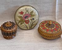 Three small lidded containers arranged side by side showing tops and designs.