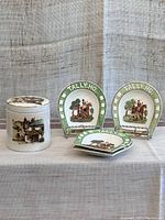 Front view showing ceramic tobacco jar with scenic image and four Wedgwood horseshoe dishes marked 'Tally Ho'