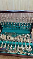 Full view of fitted case showing top row of knives and front rows of forks, spoons and serving tools