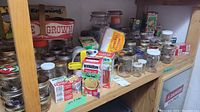 Glass canning jars, boxes of lids, and glass canisters on wooden shelves