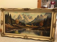 Full view of framed canvas painting showing mountain scene with lake and trees in ornate frame.
