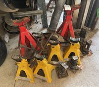 All eight jack stands shown together on floor including 3 red, 4 yellow, and 1 black jack stands.