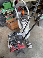 Front view of Noma tiller and Powerfist sprayer in a garage