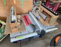 Table saw top view with red insert, fence, miter gauge and two wooden roller supports on either side