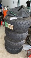 Four stacked 18.5x8.5-8 tires with several extra inner tubes on top, showing overall condition and size.