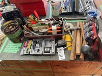 Full view of tools laid out on wooden bench showing vice, hammers, screwdrivers, pliers, tape measure, socket sets and wire wheels.