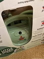Close-up view of cleaner unit with visible power switch and Bissell Little Green logo.