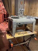 Full view of Black & Decker router on its mounted stand atop a Black & Decker Workmate 200 workbench, showing the metal stand and wooden platform parts as well as power cord.