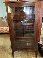 Front view of the wood and glass China cabinet showing glass door and internal shelves.