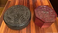Top view of both boxes together on wooden surface, showing carved patterns and shapes.