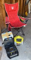Red Hummingbird folding chair with maple leaf shield logo and black armrest cup holders.