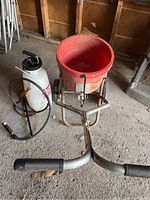 Red Central CT100B lawn seeder with hopper, wheels, and handles with grips on dirt floor in storage