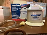 Mastercraft cordless utility pump with hoses and original box showing front and top view.