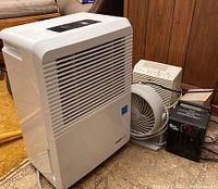 Overview of all five appliances together showing Uber Haus dehumidifier, Honeywell fan, Super Furnace heater, Holmes and Fresh air purifiers on floor.