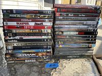 Photo showing stack of DVDs in original cases, titles clearly visible including Hellraiser, Deadpool, Rambo, and more.