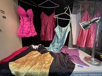 Overview of all the ladies delicate items including dresses and lingerie in various colors laid out on a table and hung on hangers.