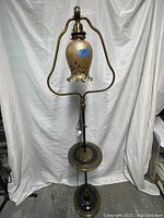 Full view of the antique brass floor lamp showing the glass shade, brass frame, tray, and base.