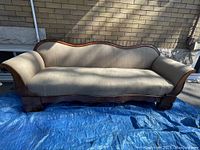 Front view of antique Victorian sofa with walnut frame and beige upholstery, showing overall shape and design.