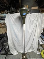 Full view of the tall floor lamp showing metal shade, stand, and decorative base.