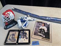 Photo showing all items in the lot together including helmet replica, figure, hockey stick, and two signed hockey cards