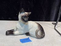 Image of a vintage Siamese-style Beswick cat figurine lying down showing the detailed paintwork and glaze.