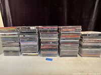 Five stacks of assorted music CD jewel cases arranged on a table
