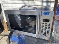 Front and right side view of the Danby Designer stainless steel microwave oven with control panel and handle visible.