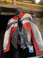 Motorcycle jacket hanging on a hanger, showing red, black and white mesh fabric with zipper front and size medium