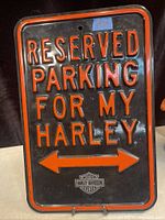 Front view of vintage Harley-Davidson metal sign with red embossed lettering and logo on black background.