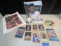 Photo showing the signed baseball with stand, signed photo of player, signed artistic photo of Fergie Jenkins, baseball cards spread in front, two Toronto Blue Jays patches.