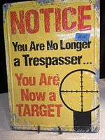 Photo of a rectangular vintage metal sign with yellow background and red and black text; shows some wear and aged patina.