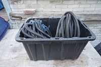 Two black coiled rolls of corrugated plastic tubing in a black plastic container, shown from above and edge.