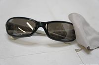 Close up photo of black Bolle sunglasses with tinted lenses and gray microfiber cloth