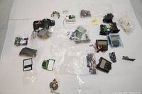 Top-down photo of various scattered Canon DSLR camera parts, circuit boards, and electronic components laid out on a white surface.
