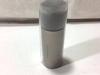 Front view of the BareMinerals foundation brush showing dense synthetic bristles and silver matte cylindrical handle with logo.