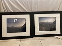 Two side-by-side framed photographs resting on tile floor, showing Israeli landscape views with black frames and white mats.