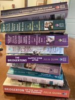 Stacked view of 8 Julia Quinn novels showing titles and author names on spines, confirming presence of Bridgerton series and other novels.