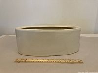 White ceramic planter pot placed on a flat surface with a ruler for size reference, showing width approximately 12 inches.