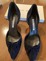 Pair of navy suede pumps displayed from above with box visible