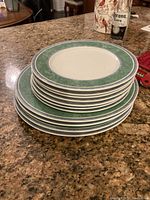 Stack of 4 dinner plates and 7 smaller salad/dessert plates showing the green and blue patterned rims on white china, displayed on a granite counter.