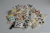 Overview of approximately 30 sets of assorted buttons on paper cards in multiple colors including yellow, blue, cream, pink, and brown.