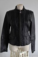 Front view of Danier black leather jacket on mannequin, showing vertical stitch panel and flap pockets