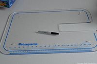 Full view of the rectangular clear acrylic Husqvarna extended platform with printed ruler along one edge and brand logo.