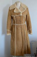 Front view of tan lambskin shearling coat with visible cream shearling collar, button closure, and two front pockets.